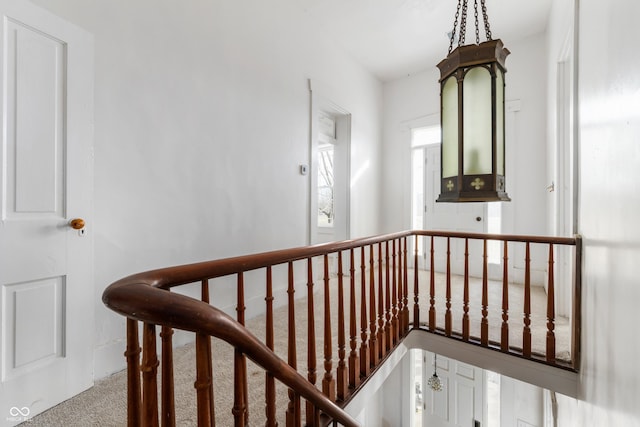 corridor with carpet floors and an upstairs landing