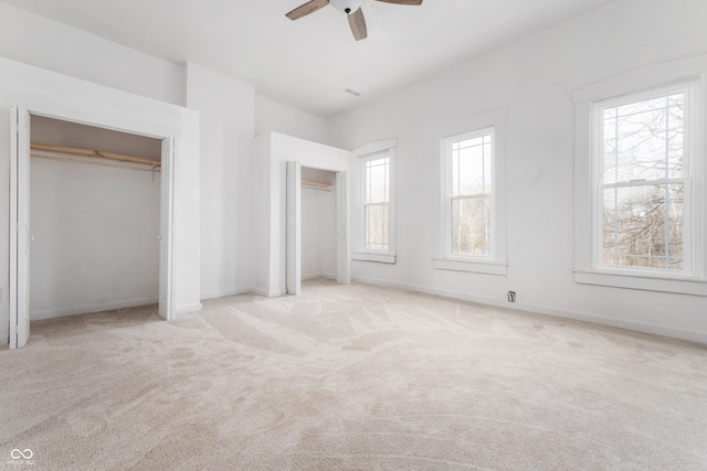 unfurnished bedroom featuring ceiling fan, multiple windows, baseboards, and carpet flooring
