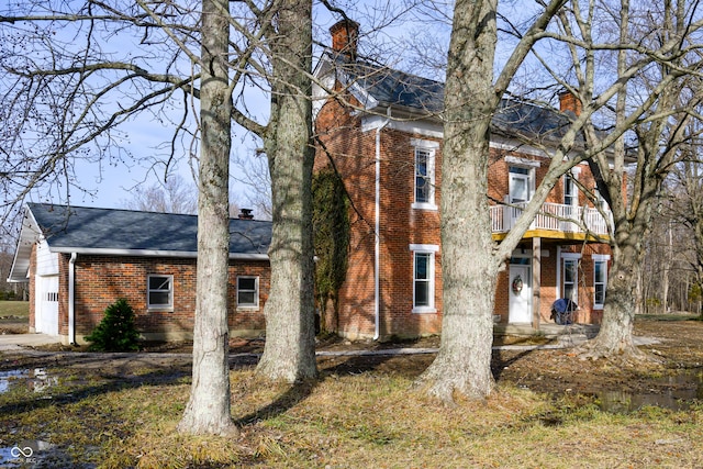 exterior space with a balcony, a chimney, and brick siding