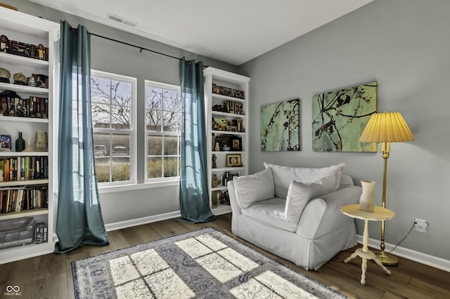 living area featuring baseboards, visible vents, and wood finished floors