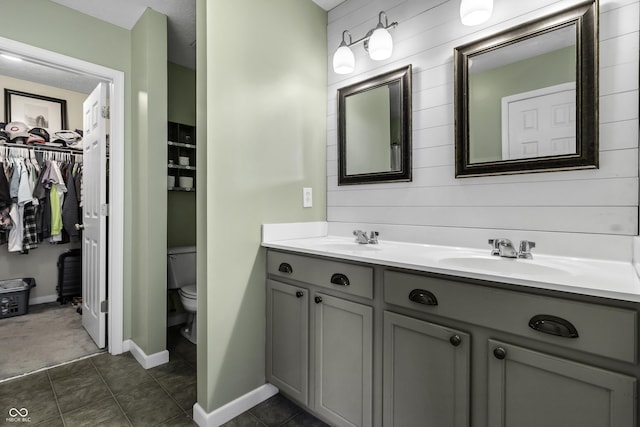 full bath featuring double vanity, a sink, toilet, and tile patterned floors