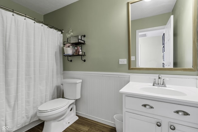 full bath featuring visible vents, wainscoting, toilet, wood finished floors, and vanity