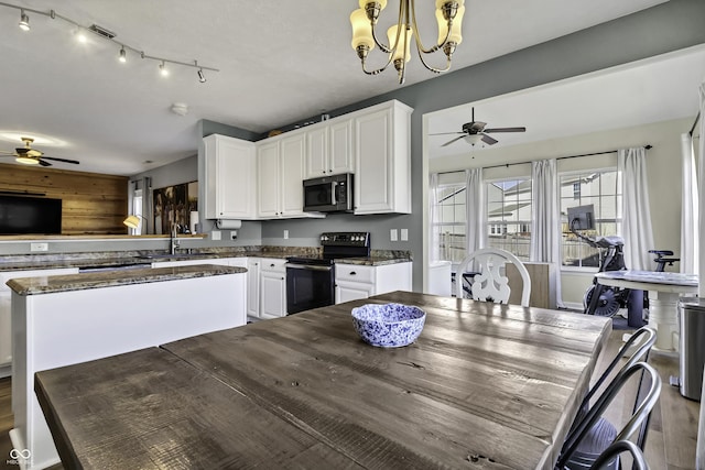 kitchen featuring black electric range, stainless steel microwave, a sink, and white cabinets