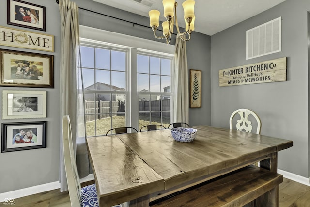 dining space with a chandelier, visible vents, baseboards, and wood finished floors