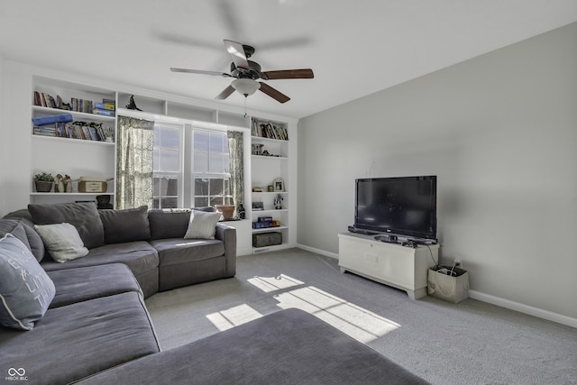 carpeted living room with ceiling fan, built in shelves, and baseboards