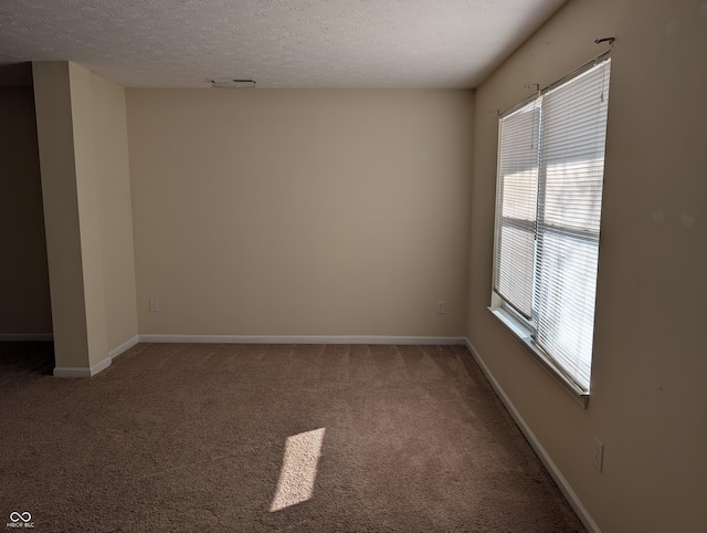 empty room featuring a textured ceiling, carpet flooring, and baseboards