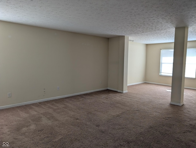 spare room with a textured ceiling, carpet floors, and baseboards