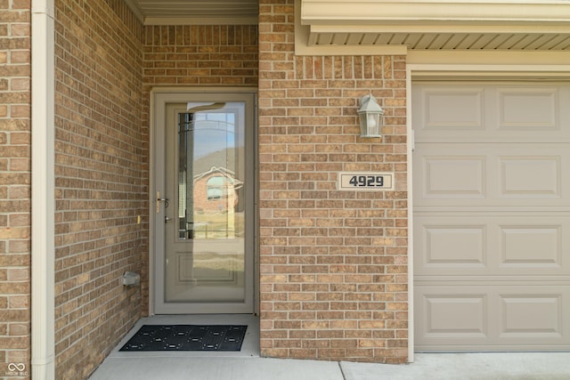 doorway to property with brick siding and an attached garage