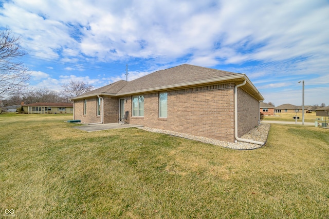 rear view of house featuring a patio area, brick siding, and a yard