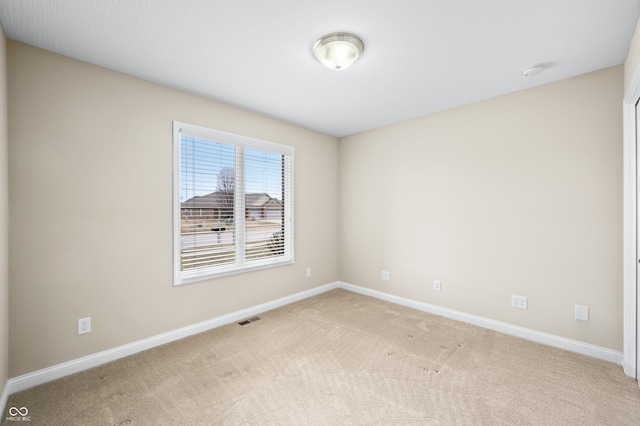 empty room featuring light carpet, visible vents, and baseboards