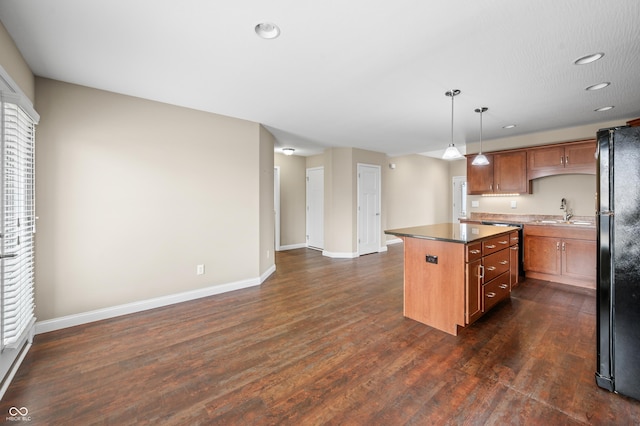 kitchen featuring dark wood-style floors, a kitchen island, brown cabinets, freestanding refrigerator, and a sink