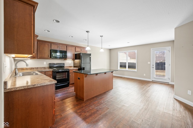 kitchen with a center island, a breakfast bar area, dark wood-type flooring, a sink, and black appliances