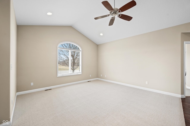 empty room featuring lofted ceiling, carpet floors, baseboards, and a ceiling fan