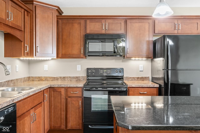 kitchen featuring black appliances, pendant lighting, brown cabinets, and a sink