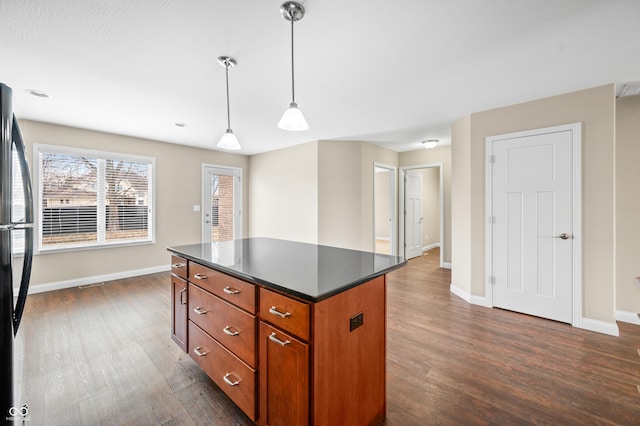 kitchen with dark wood-style flooring, dark countertops, a kitchen island, and freestanding refrigerator