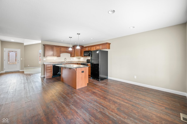 kitchen featuring dark wood-style flooring, a sink, open floor plan, a center island, and black appliances