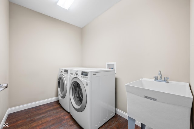 washroom featuring laundry area, baseboards, dark wood-style floors, washing machine and clothes dryer, and a sink