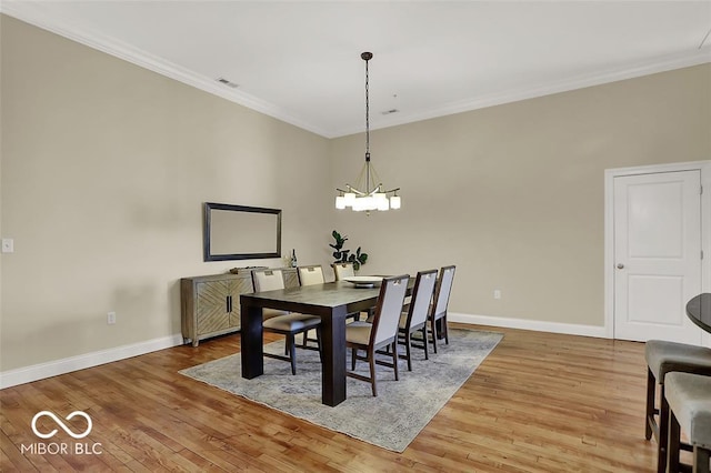 dining space with an inviting chandelier, wood-type flooring, baseboards, and crown molding