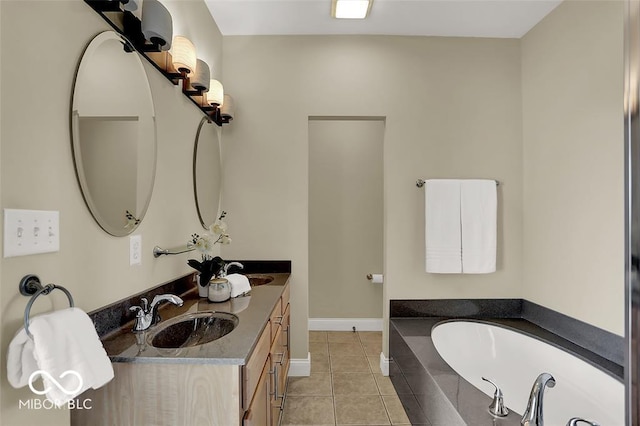 bathroom featuring a garden tub, tile patterned flooring, a sink, and baseboards