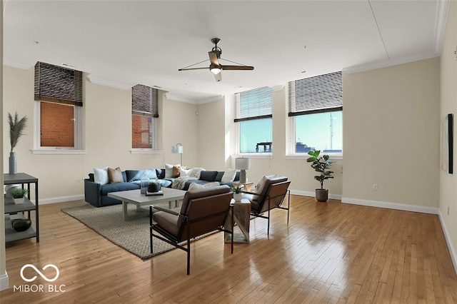 living area featuring ornamental molding, baseboards, ceiling fan, and hardwood / wood-style floors