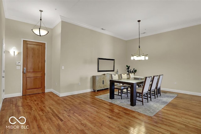 dining space with wood-type flooring, baseboards, a chandelier, and ornamental molding