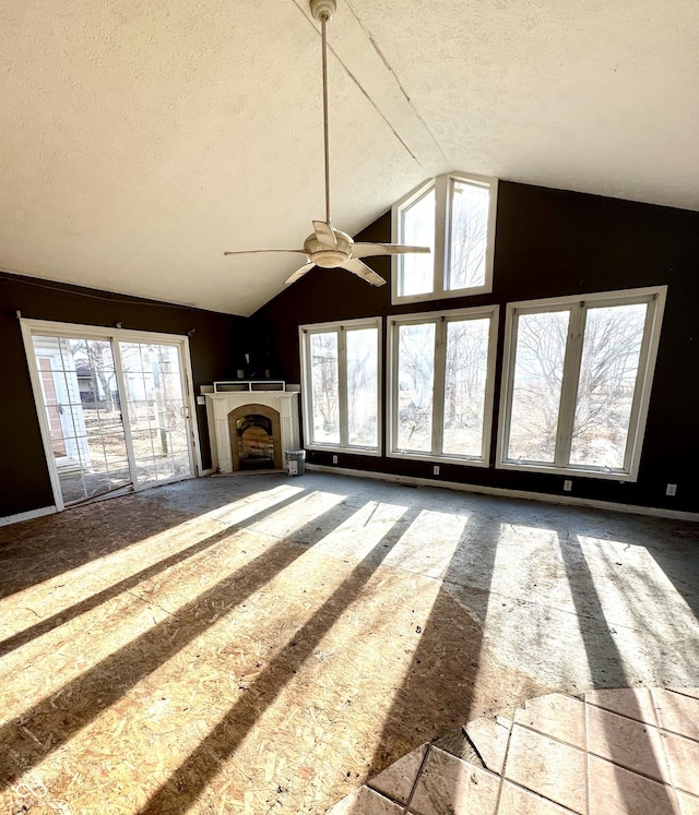 unfurnished living room with lofted ceiling, plenty of natural light, a fireplace, and a textured ceiling