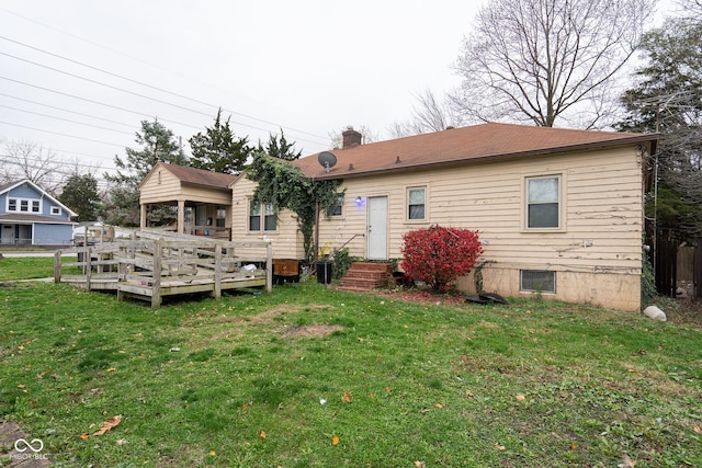 back of house featuring a deck, a yard, and a chimney