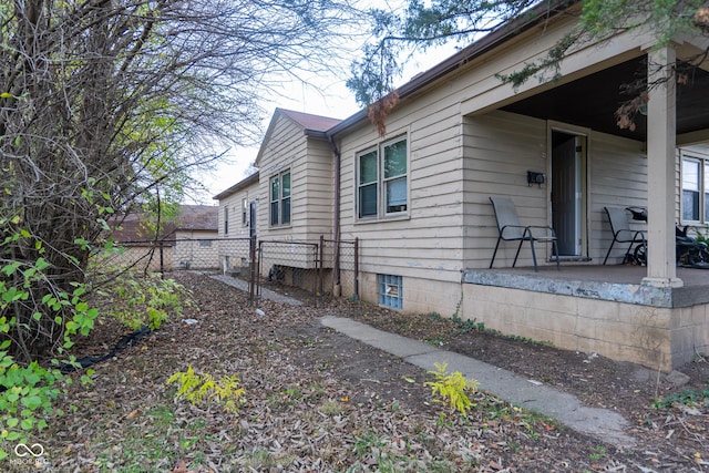 view of side of home featuring covered porch and fence