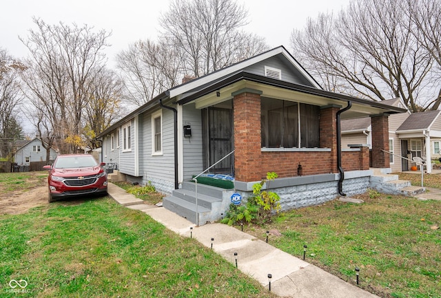 bungalow-style house featuring entry steps, brick siding, and a front yard