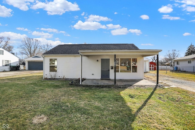 bungalow with an outbuilding, a detached garage, fence, a front yard, and a patio area