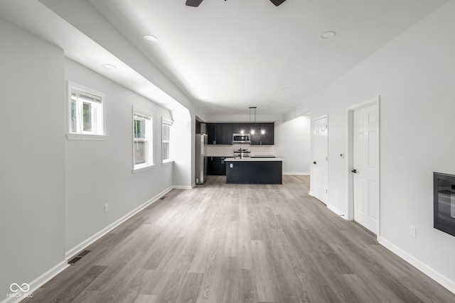 unfurnished living room featuring ceiling fan, wood finished floors, visible vents, and baseboards