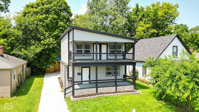 rear view of house featuring covered porch, a yard, fence, and a balcony