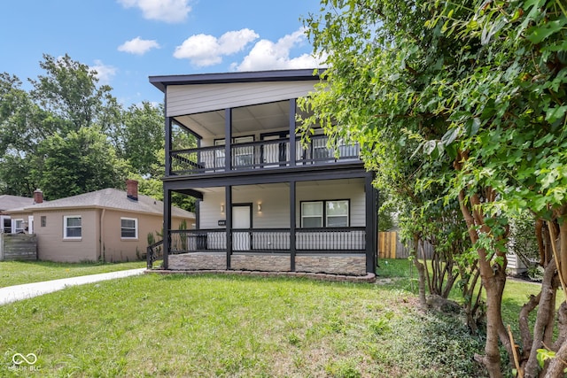 view of front of home with a porch, a front yard, fence, and a balcony