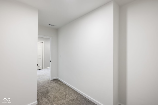 hallway with carpet, visible vents, and baseboards