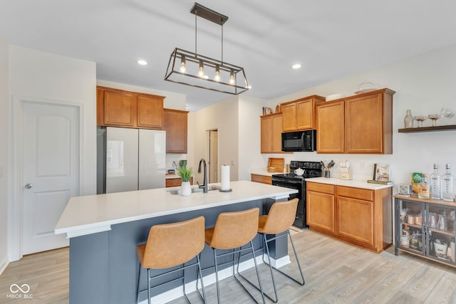 kitchen featuring black appliances, light wood-type flooring, light countertops, and brown cabinets