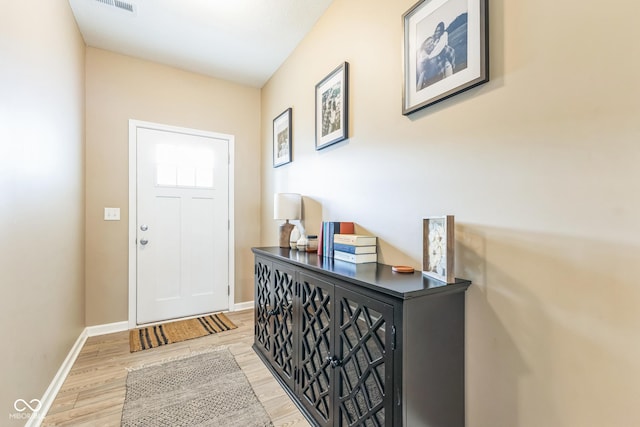 foyer with light wood finished floors, visible vents, and baseboards