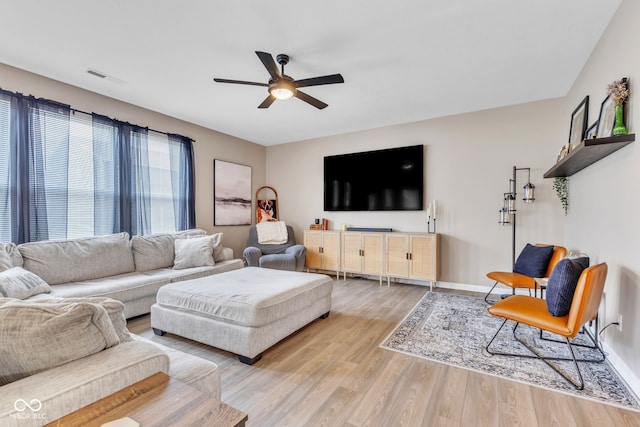 living area featuring visible vents, baseboards, light wood-style flooring, and a ceiling fan