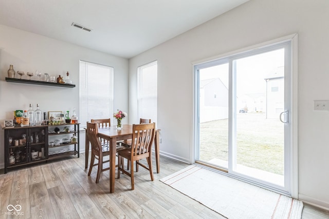 dining space featuring baseboards, visible vents, and light wood finished floors