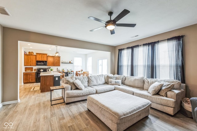 living room featuring light wood-style floors, ceiling fan, and visible vents