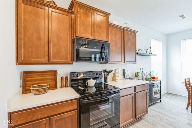 kitchen featuring visible vents, light wood-style floors, light countertops, black appliances, and open shelves