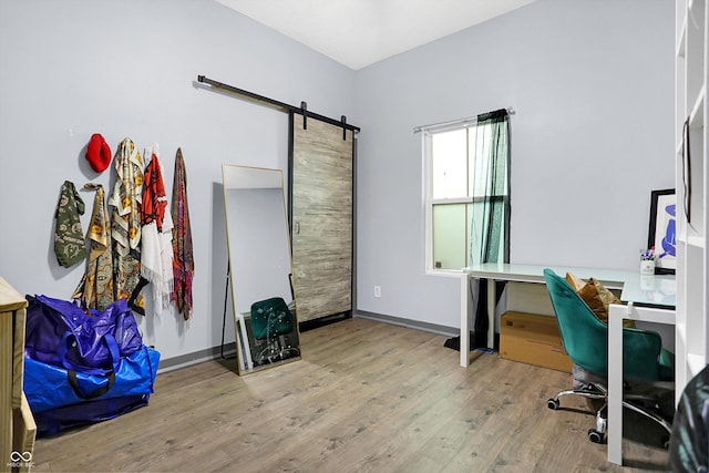 office space with wood finished floors, baseboards, and a barn door