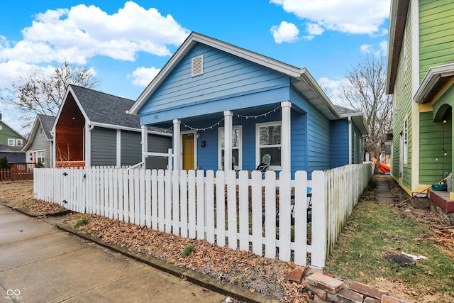 view of front of house featuring a porch, a shingled roof, and a fenced front yard