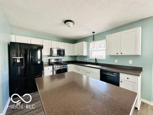 kitchen featuring dark countertops, black appliances, white cabinetry, and a sink