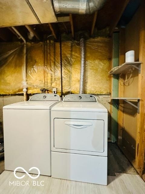 clothes washing area featuring light wood-style floors, laundry area, and washing machine and clothes dryer