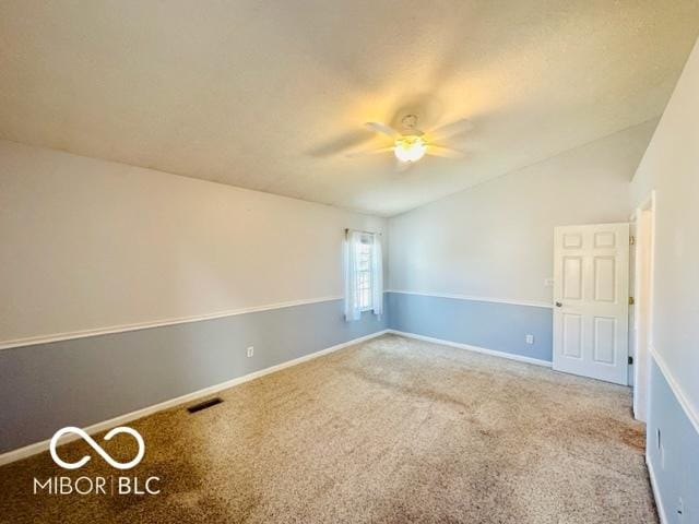 unfurnished room featuring carpet, lofted ceiling, visible vents, a ceiling fan, and baseboards