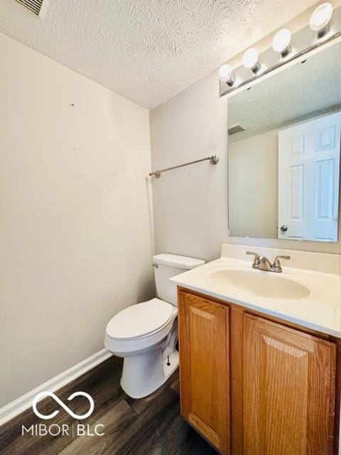 bathroom featuring toilet, a textured ceiling, wood finished floors, and vanity