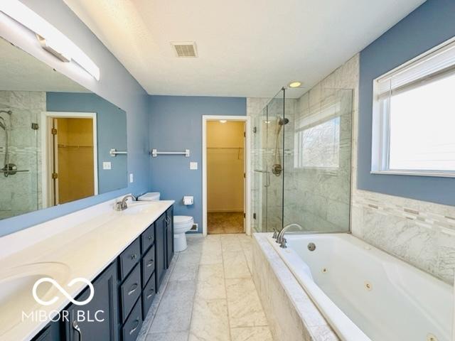 full bathroom with toilet, a sink, visible vents, a shower stall, and a tub with jets