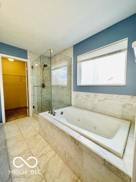 bathroom featuring a spacious closet, a stall shower, and a jetted tub