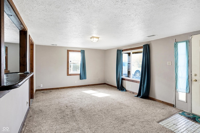 unfurnished living room featuring carpet floors, a healthy amount of sunlight, visible vents, and baseboards