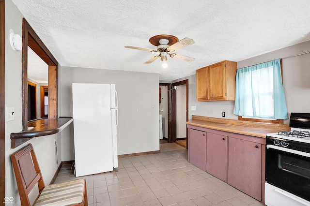 kitchen featuring ceiling fan, a textured ceiling, light countertops, freestanding refrigerator, and gas stove